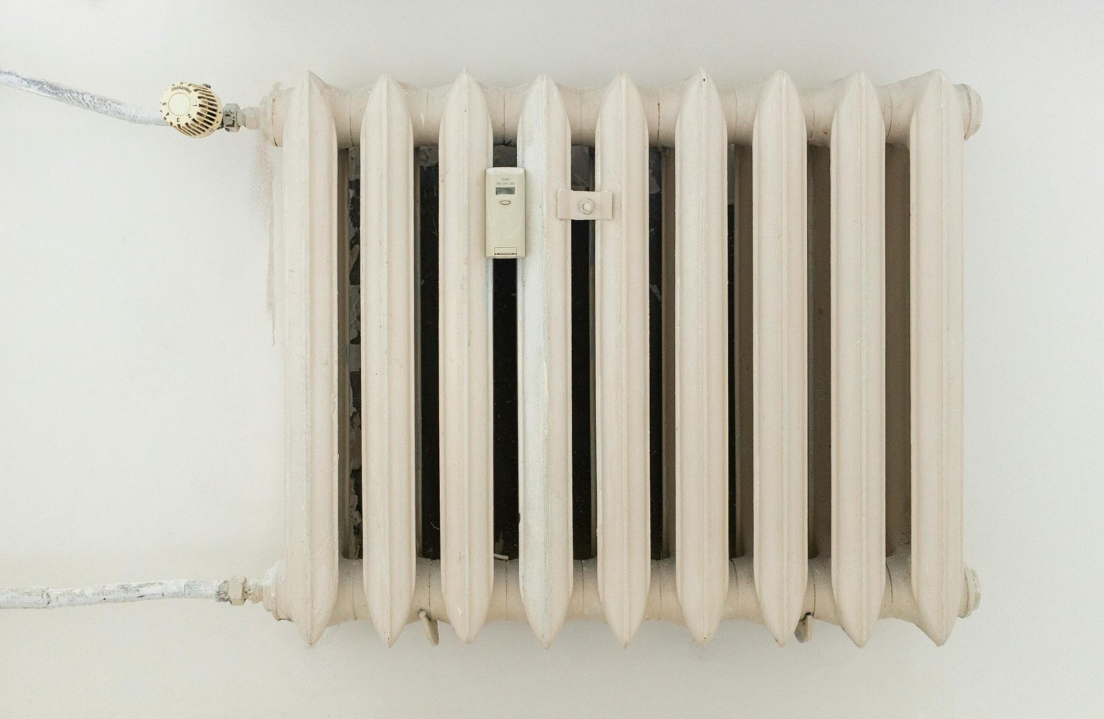 pexels-photo-12034871-12034871 A classic white metal radiator on a plain wall, showcasing minimalist interior design.